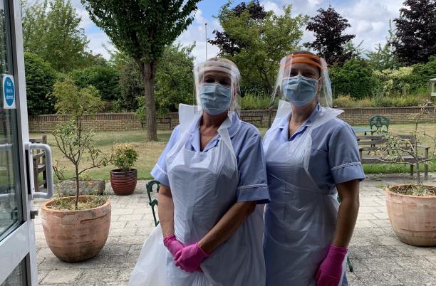 Two nurses in full PPE outside a building