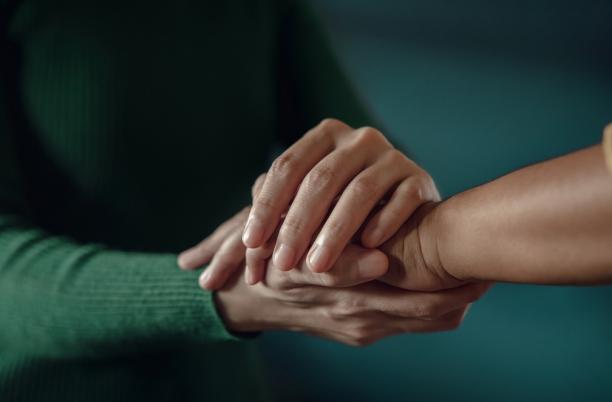 Stock photo of two people holding hands supportively