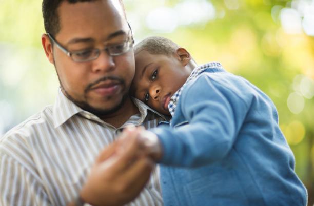 Father carrying young son, sadness