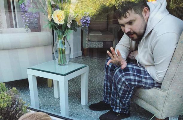 Tom, waving to his daughter Poppy at St Luke's Hospice in Plymouth