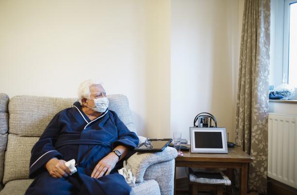 Man with mask on looking out of window