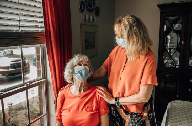 Daughter talking with her mother wearing protective mask