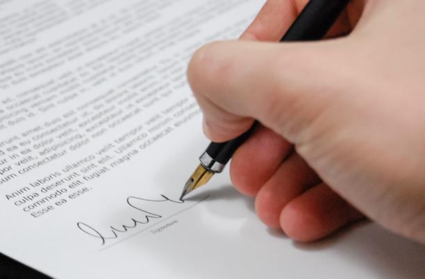 A stock photo of someone signing a legal document