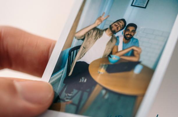 Person holding a polaroid of two people smiling