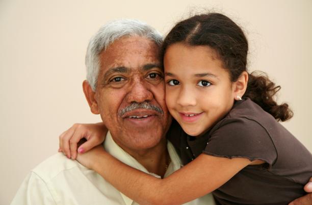 a young girl with dark hair hugs her Grandad with grey hair