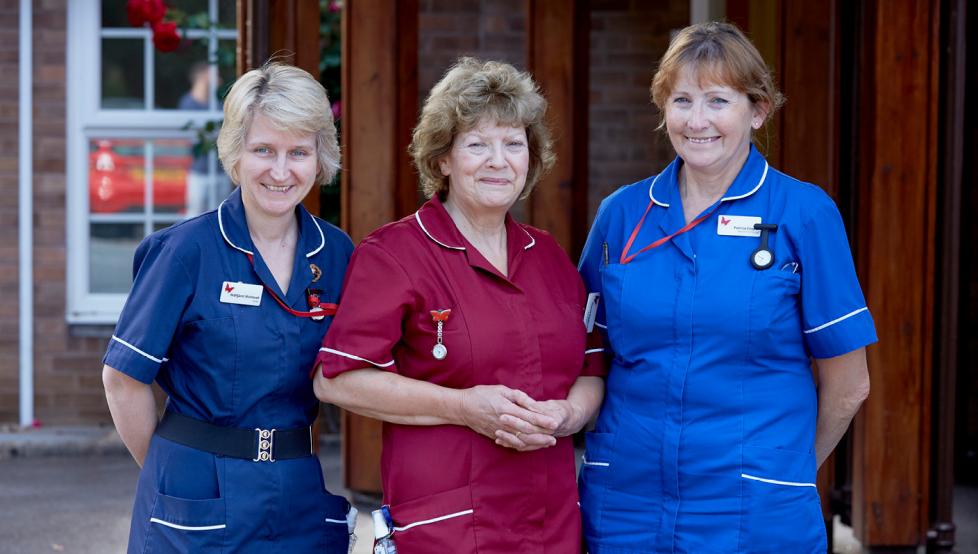 Three nurses standing outside of a building