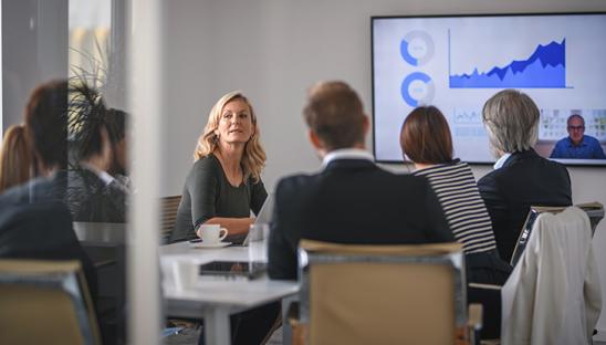 Stock photo of a group of men and women, seated, having a board meeting